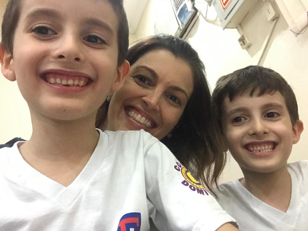 Os gêmeos autistas Pietro e Lorenzo posam sorrindo com sua mãe entre os dois